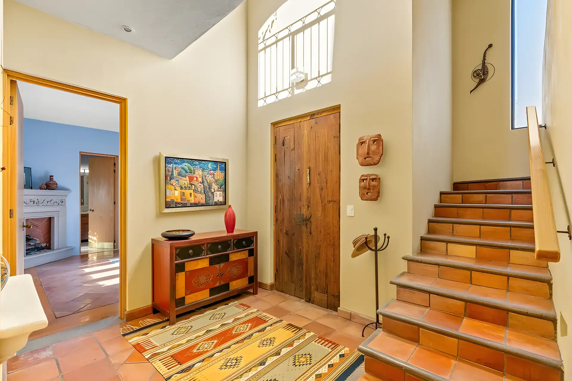Casa Privada, entry foyer with a carved door, a painted chest and a staircase with a high window, San Miguel de Allende
