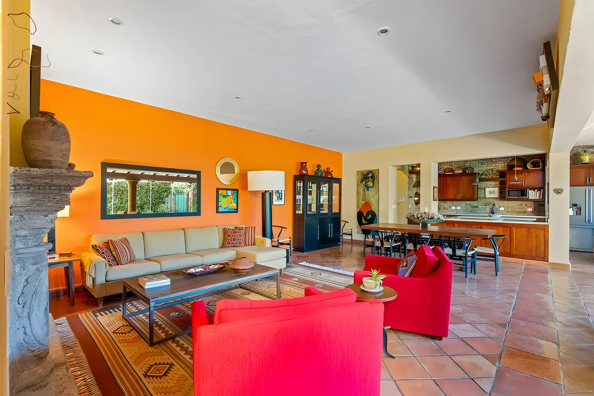 Casa Privada, living room with red armchairs, a beige sofa, an orange wall and an open kitchen and dining area, San Miguel de Allende