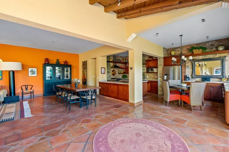 Casa Privada, dining area with a wood table and chairs beside a kitchen with a brick wall and a tall blue china cabinet, San Miguel de Allende
