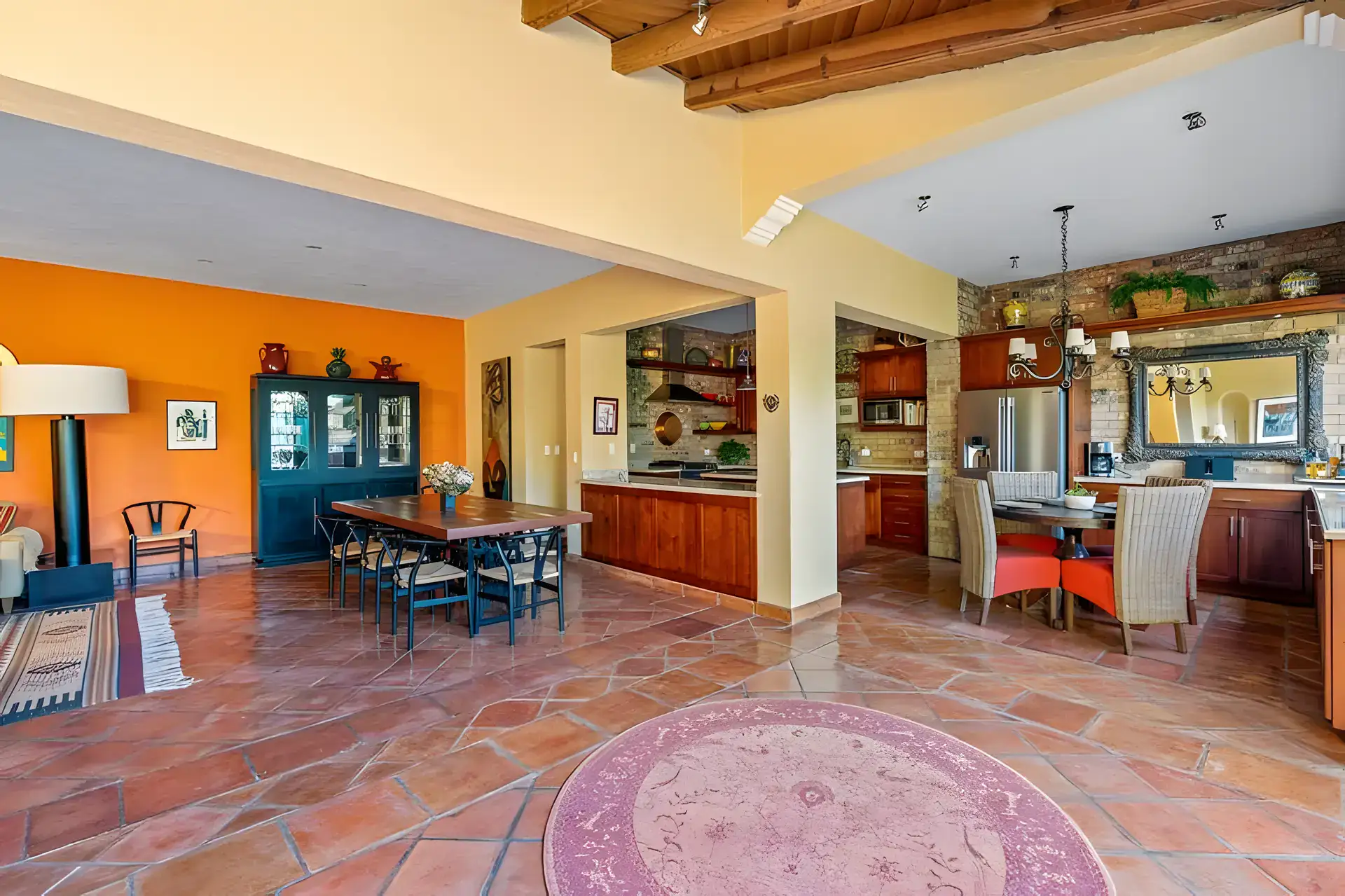 Casa Privada, dining area with a wood table and chairs beside a kitchen with a brick wall and a tall blue china cabinet, San Miguel de Allende