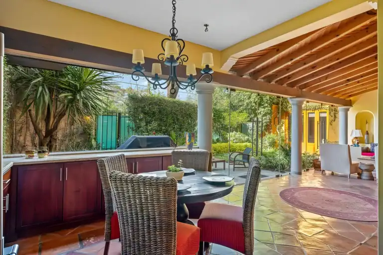 Casa Privada, breakfast table with wicker chairs, a chandelier and glass walls to the garden, San Miguel de Allende