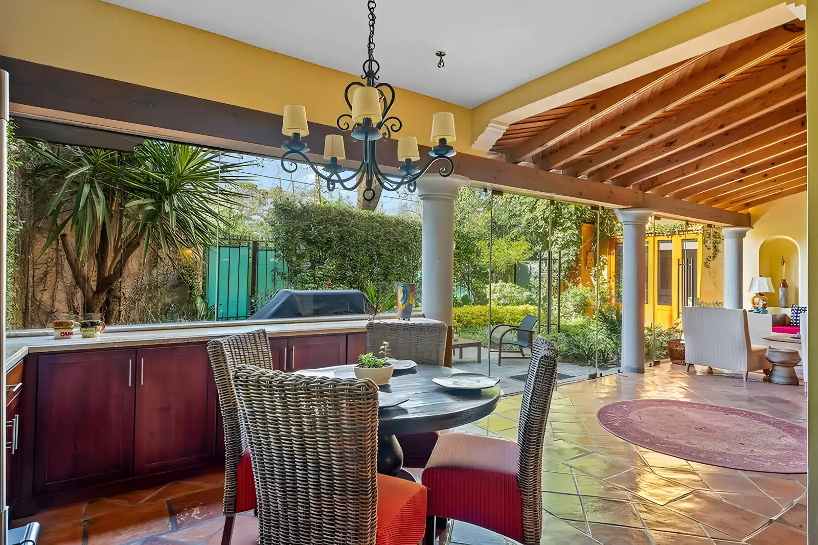 Casa Privada, breakfast table with wicker chairs, a chandelier and glass walls to the garden, San Miguel de Allende