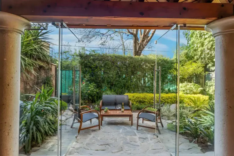 Casa Privada, garden patio with a flagstone floor and lounge chairs seen through glass walls, San Miguel de Allende