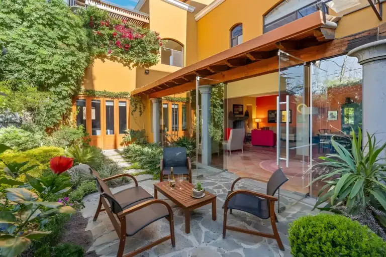Casa Privada, garden seating area with stone paving, wood chairs, bougainvillea and shrubs, San Miguel de Allende