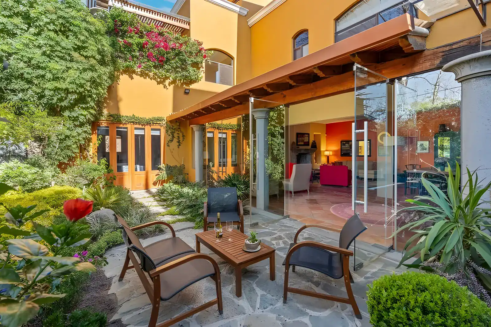 Casa Privada, garden seating area with stone paving, wood chairs, bougainvillea and shrubs, San Miguel de Allende