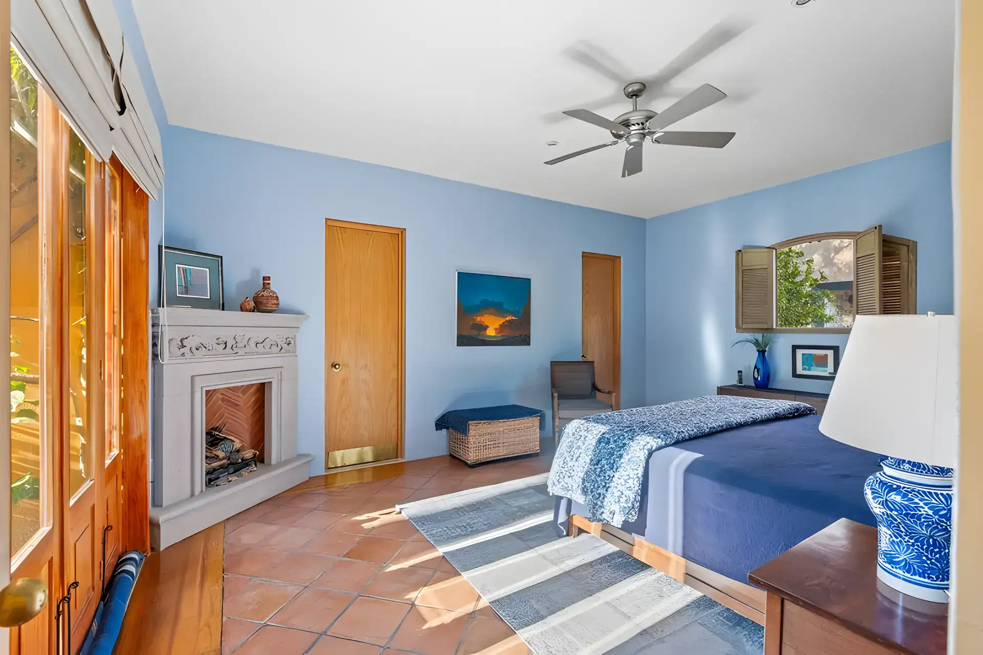 Casa Privada, bedroom with blue walls, a corner fireplace, a blue patterned bedspread and a ceiling fan, San Miguel de Allende