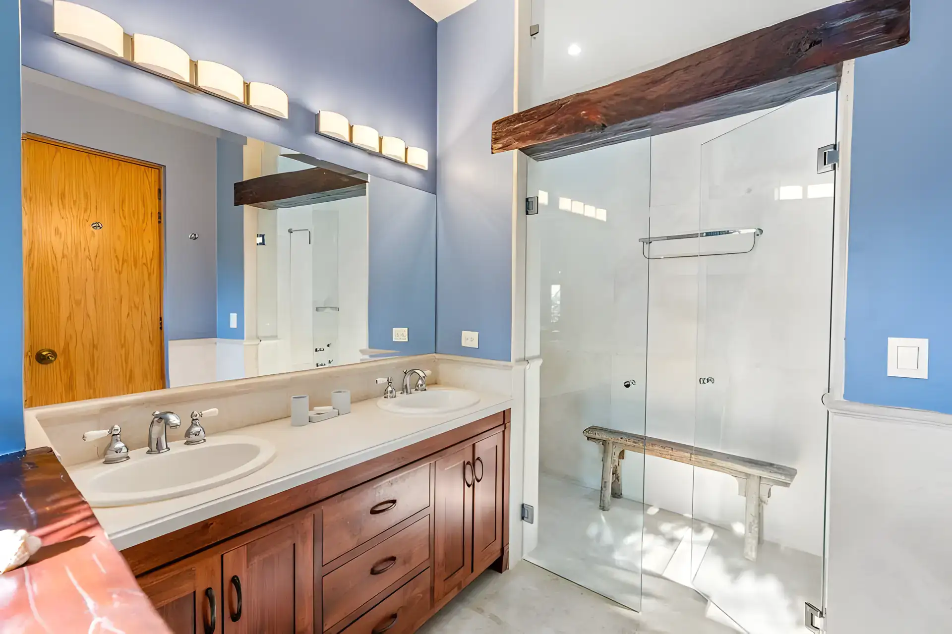 Casa Privada, bathroom with a double vanity, wood beam over a glass shower and a bench, San Miguel de Allende