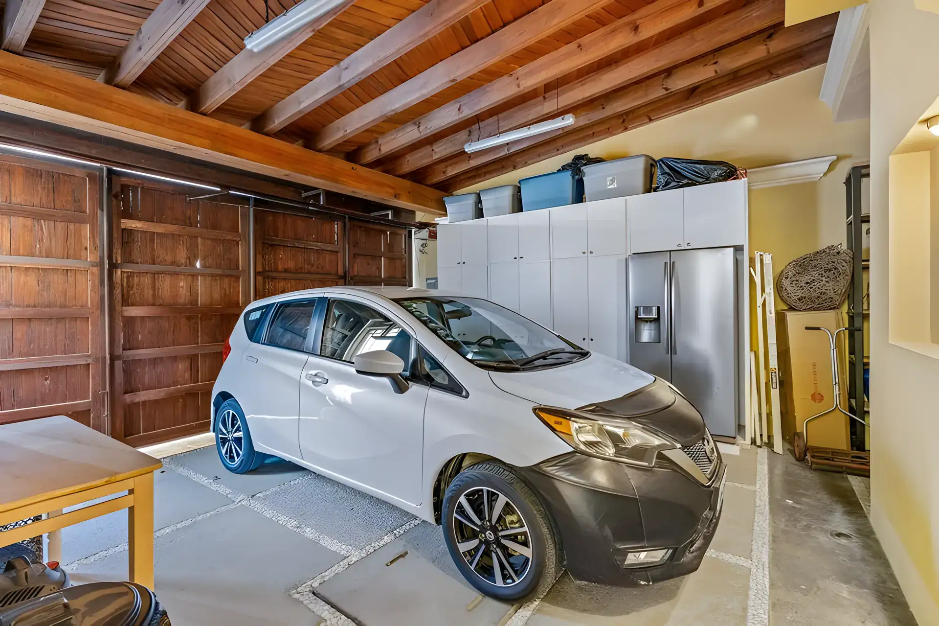 Casa Privada, garage with a car, wood doors and white storage cabinets with a refrigerator, San Miguel de Allende