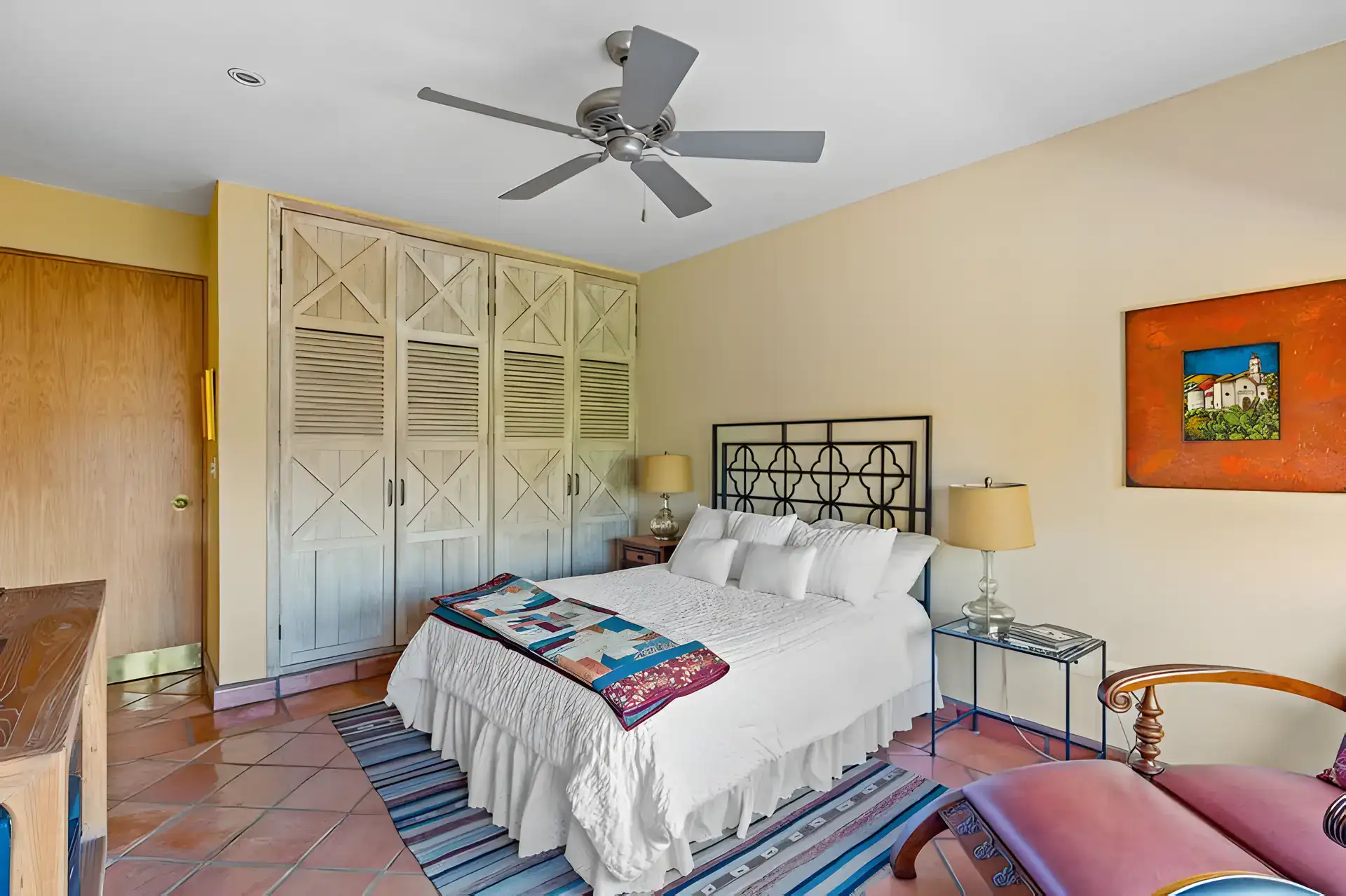 Casa Privada, bedroom with a wood louvered wardrobe, an iron headboard and a patterned runner, San Miguel de Allende