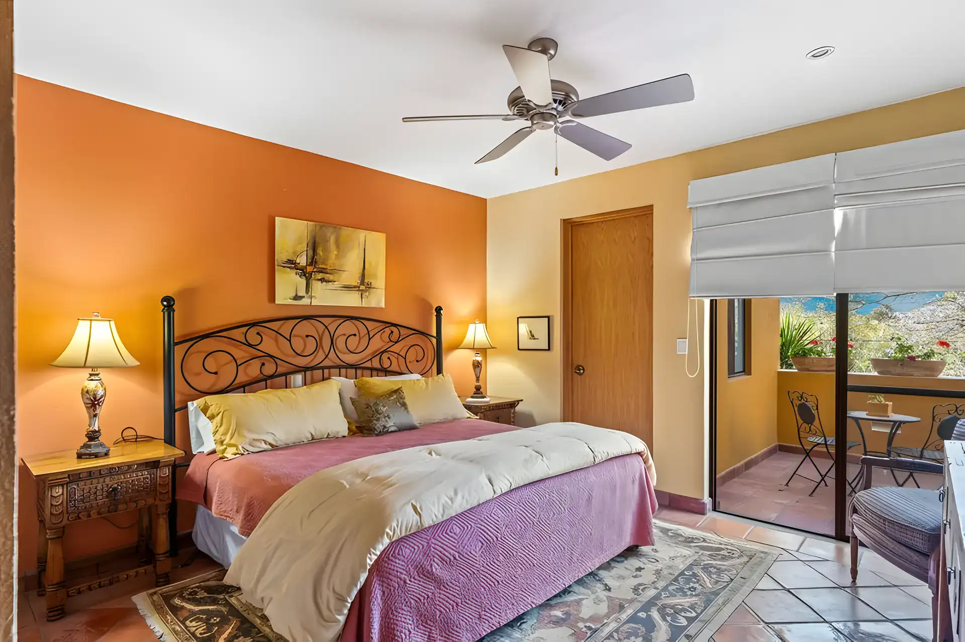 Casa Privada, bedroom with an orange wall, a wrought-iron bed, a pink bedspread and a balcony, San Miguel de Allende