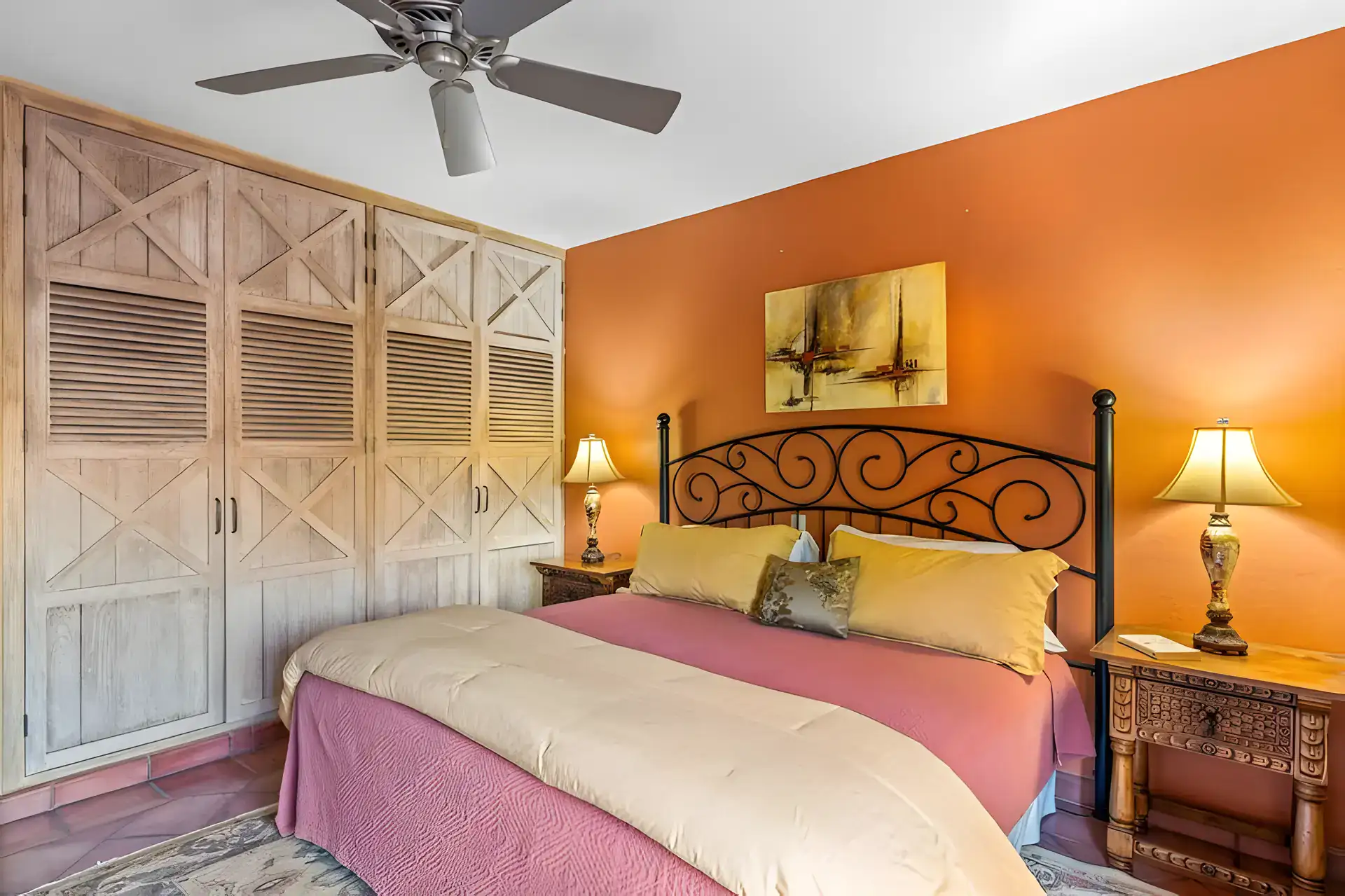 Casa Privada, bedroom with a louvered wardrobe, an orange wall and a wrought-iron bed, San Miguel de Allende