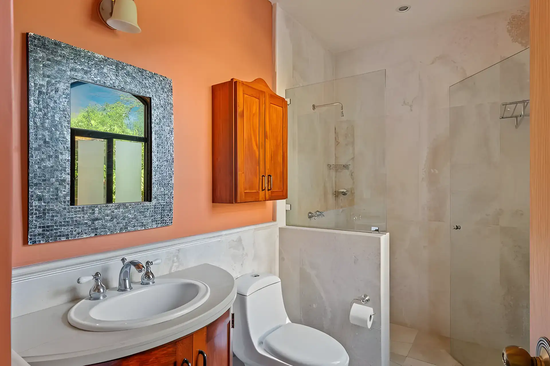 Casa Privada, bathroom with a mosaic-framed mirror, an orange wall, a round vanity and a shower, San Miguel de Allende