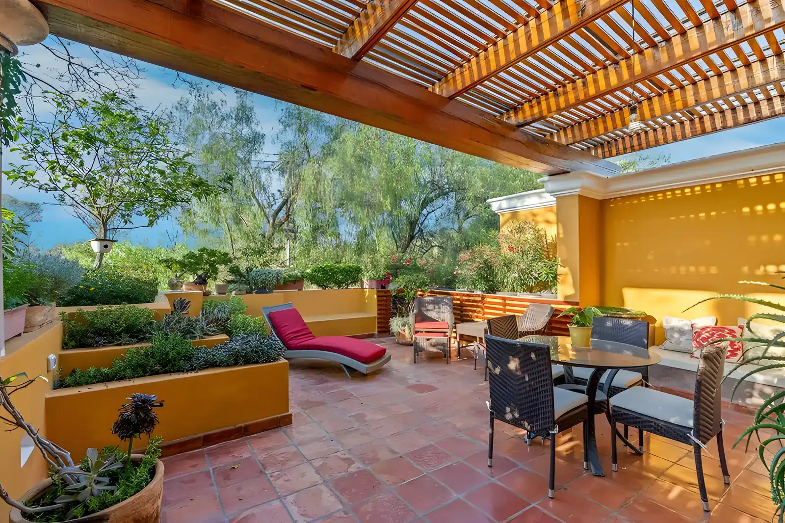 Casa Privada, rooftop terrace with a pergola, a lounge chair, planter beds, dining set and views of trees, San Miguel de Allende