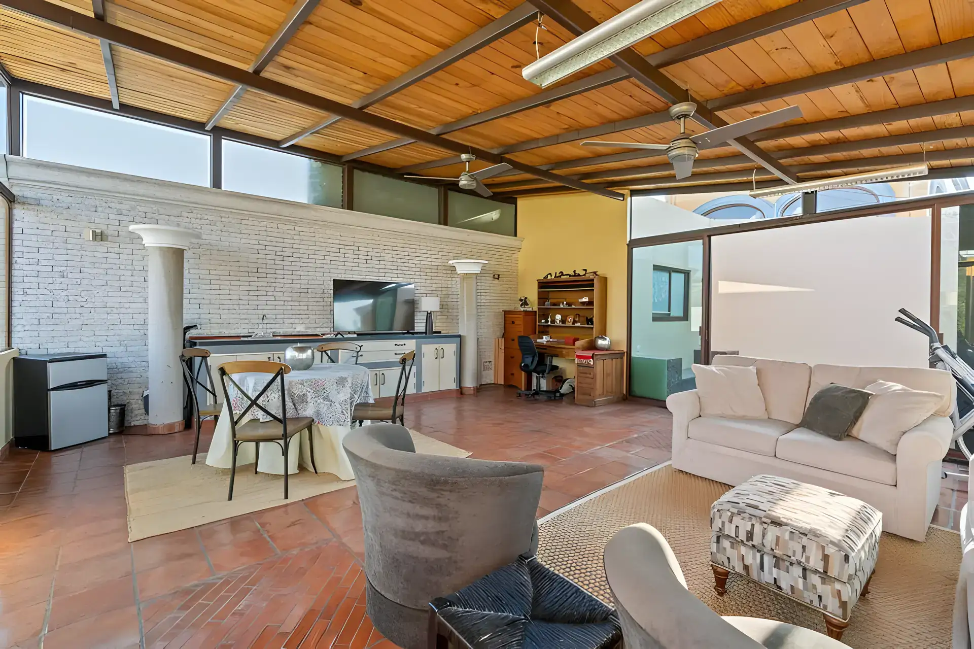 Casa Privada, covered rooftop room with a white sofa, a table with chairs, a desk and a brick wall, San Miguel de Allende