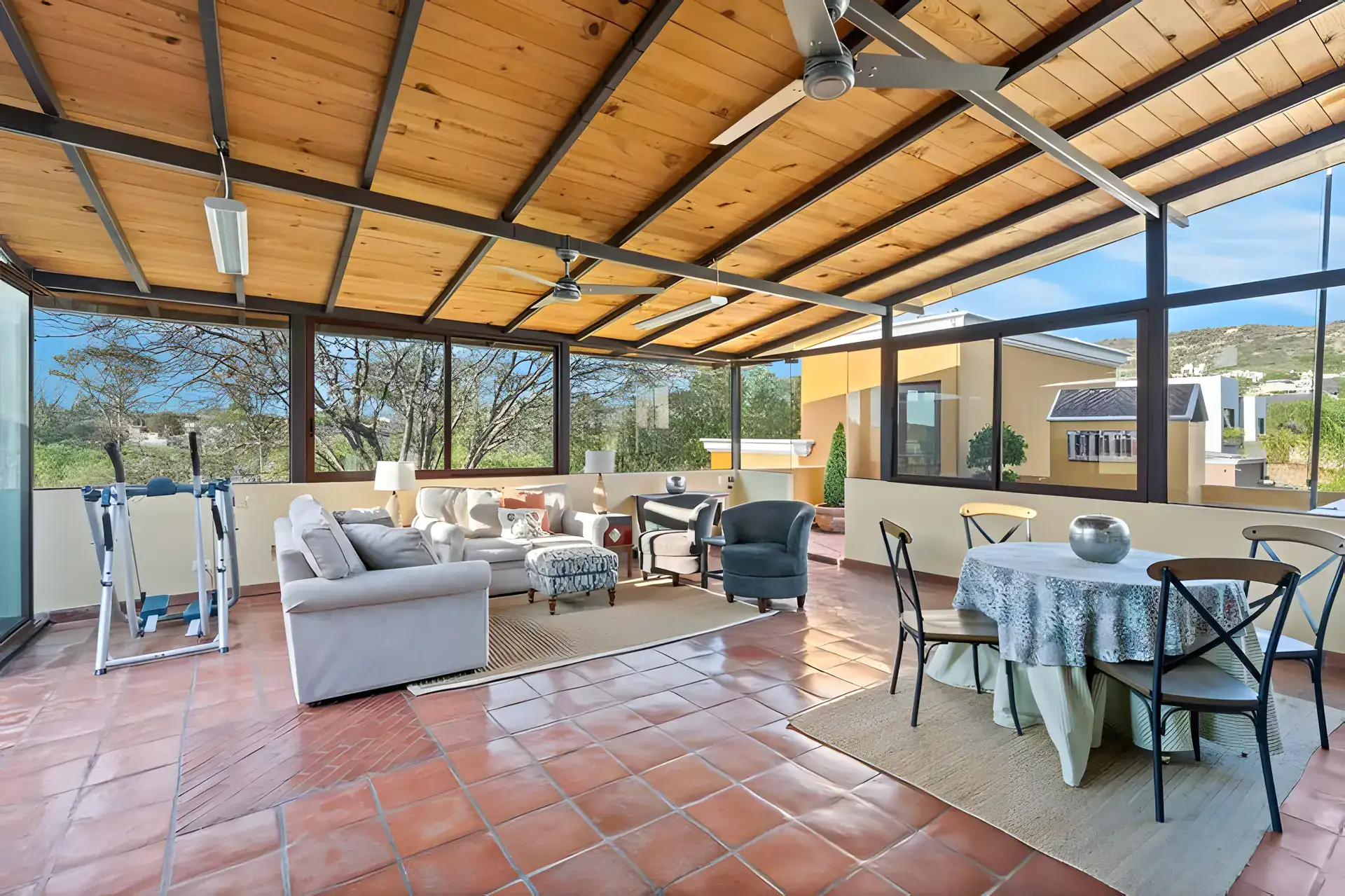 Casa Privada, covered rooftop room with a sofa, a dining table and an exercise machine and views of green hills, San Miguel de Allende