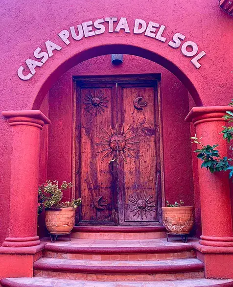 Casa Puesta del Sol, arched red entrance with the house name above a carved wood door, San Miguel de Allende
