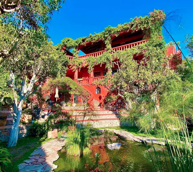 Casa Puesta del Sol, red house above a garden pond with stone paths, San Miguel de Allende