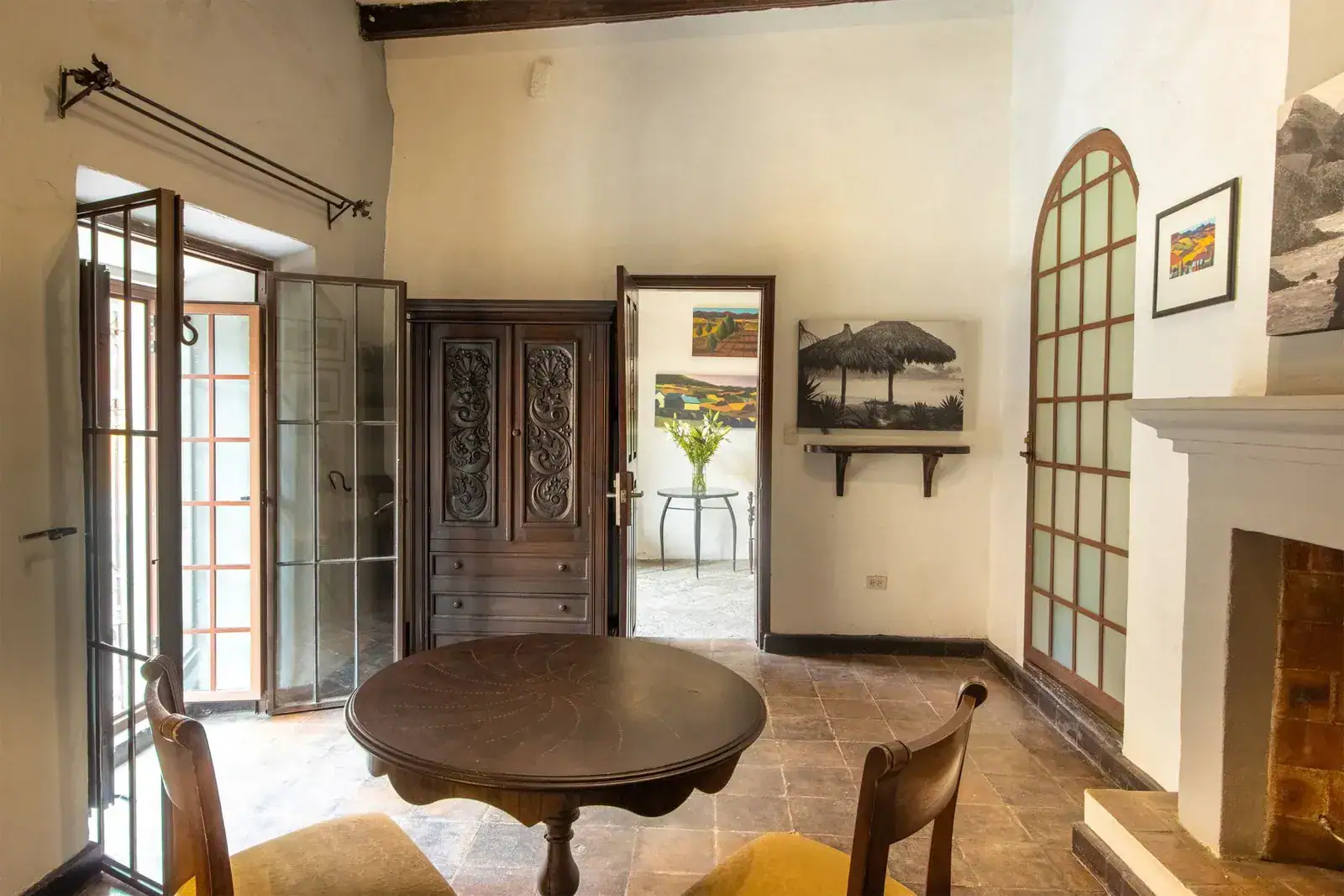 Casa Quetzal Hotel, suite sitting room with a round wood table, a fireplace and open barred French doors, San Miguel de Allende