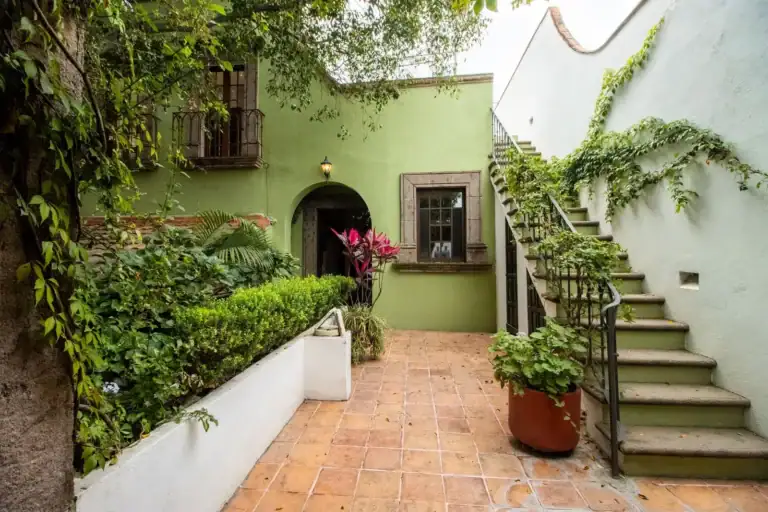 Casa Quetzal Hotel, green courtyard with a staircase, planter beds and an arched doorway, San Miguel de Allende