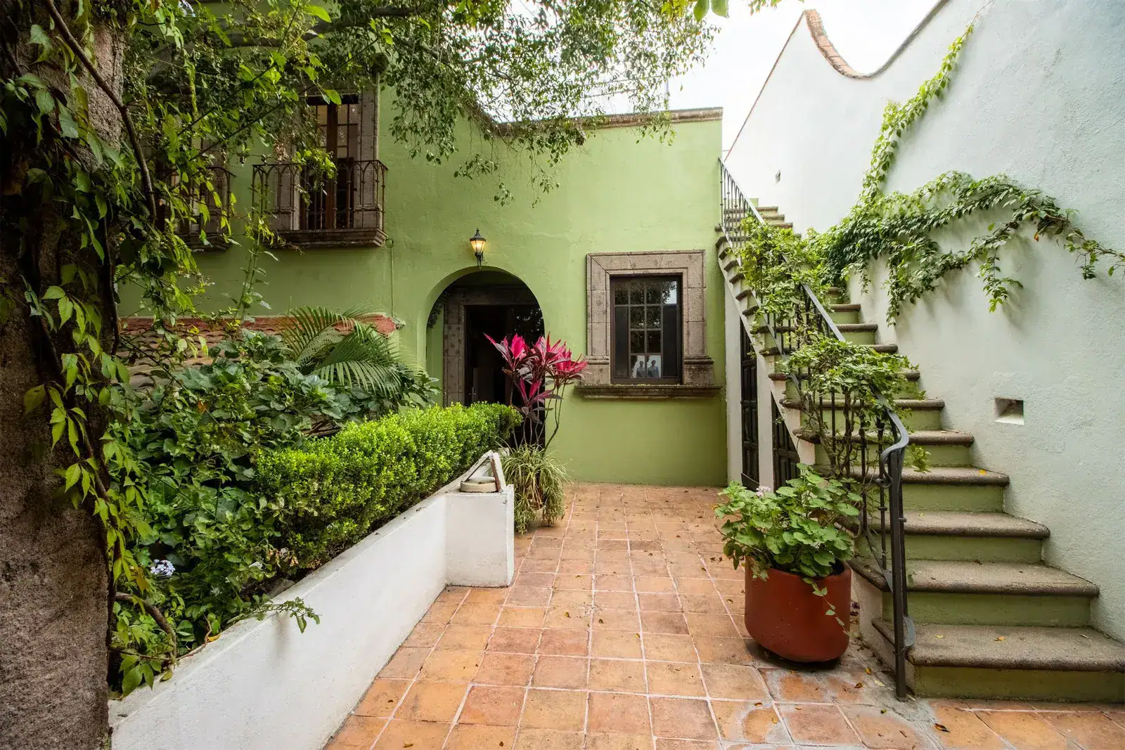 Casa Quetzal Hotel, green courtyard with a staircase, planter beds and an arched doorway, San Miguel de Allende