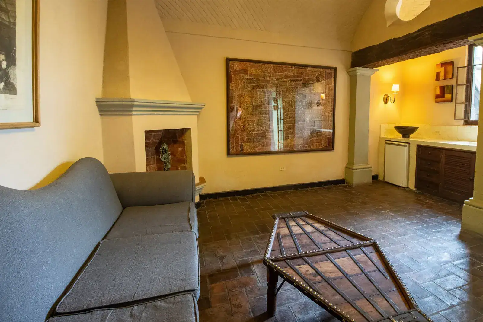 Casa Quetzal Hotel, sitting room with a gray sofa, corner fireplace and a kitchenette, San Miguel de Allende