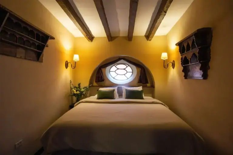 Casa Quetzal Hotel, bedroom with an arched headboard niche, a round window and a beamed ceiling, San Miguel de Allende