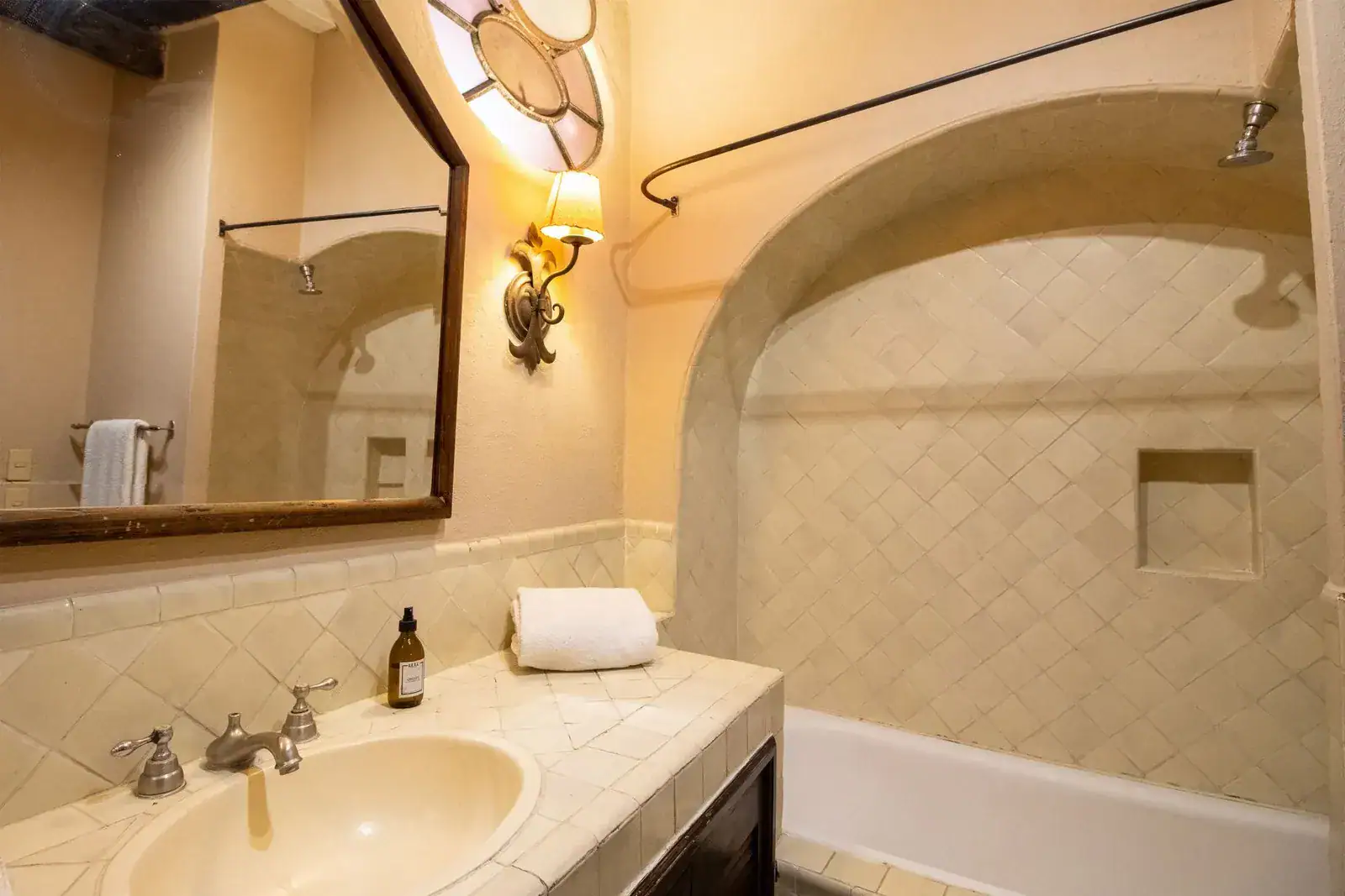 Casa Quetzal Hotel, bathroom with an arched shower alcove, tiled vanity and a round mirror, San Miguel de Allende