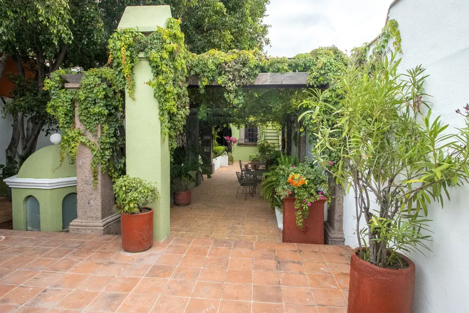 Casa Quetzal Hotel, vine-covered walkway with a column, planters and a patio at the end, San Miguel de Allende