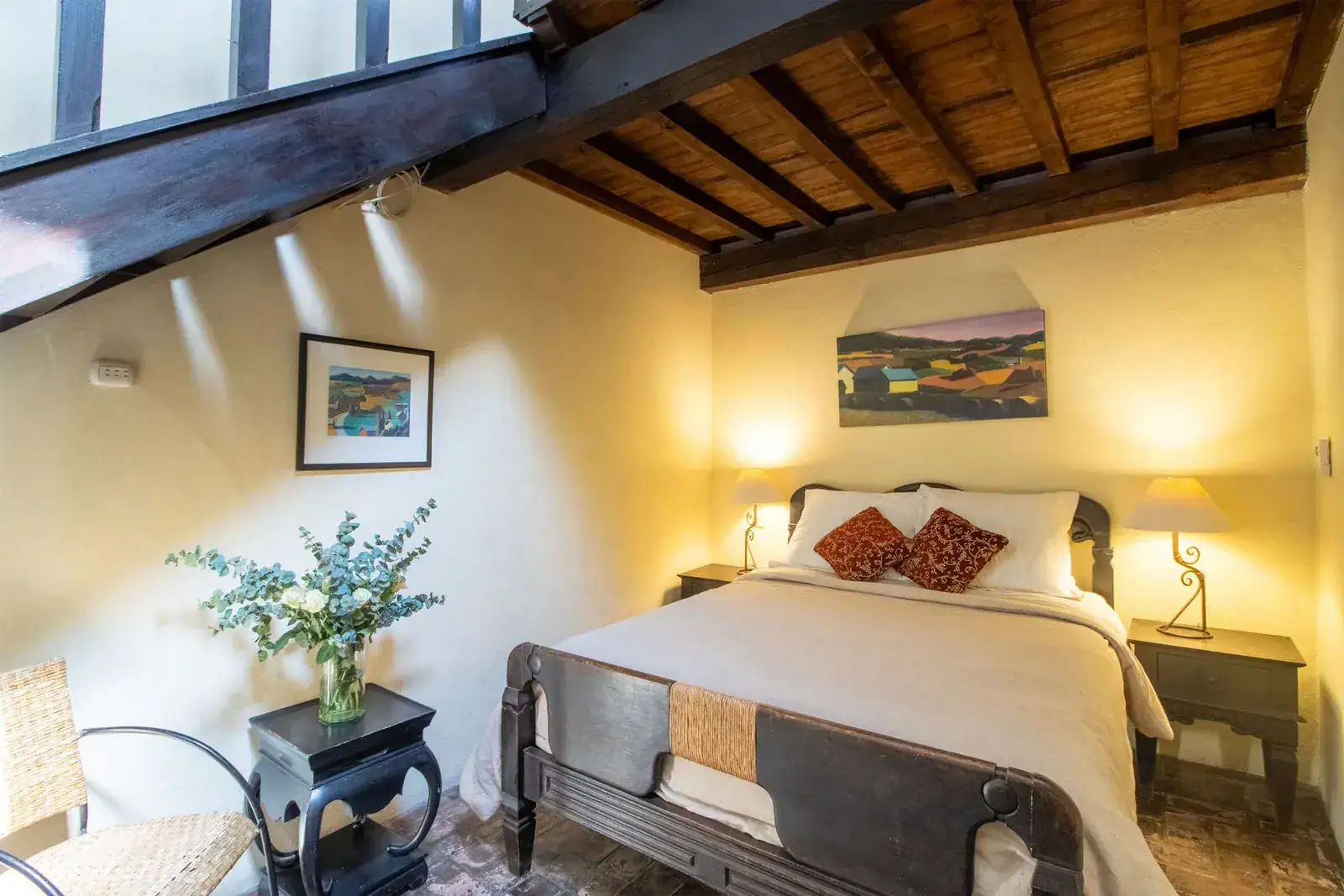 Casa Quetzal Hotel, bedroom with a carved dark wood bed, orange accent pillows and a wood ceiling, San Miguel de Allende