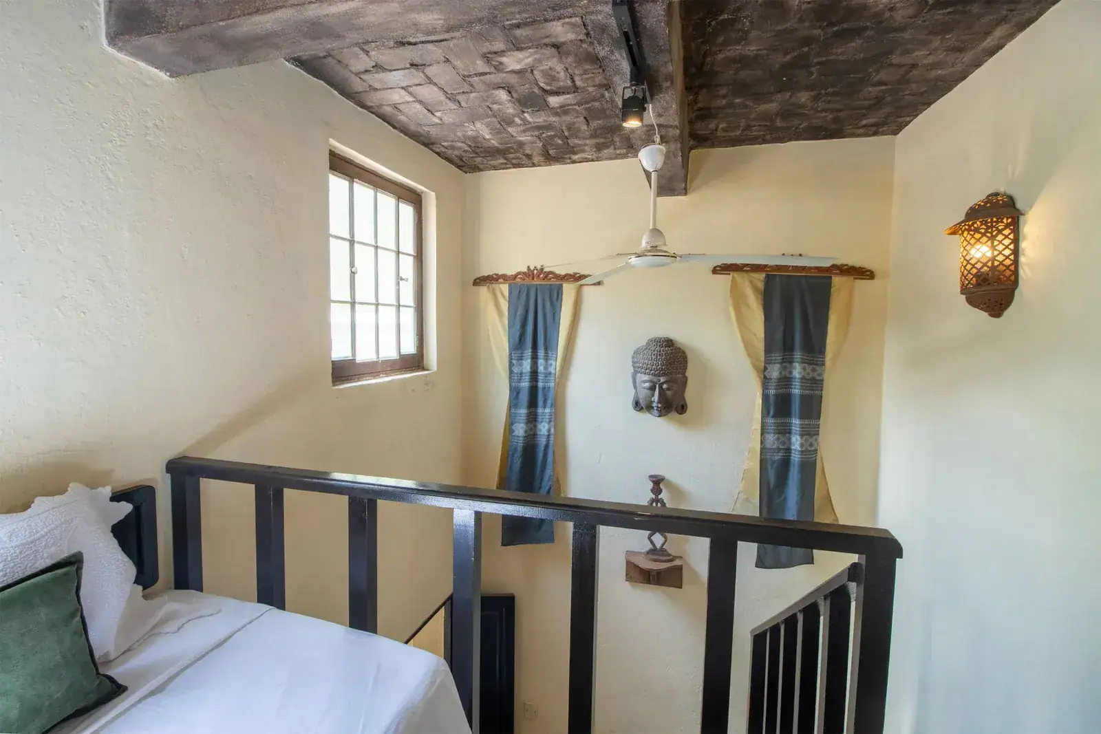 Casa Quetzal Hotel, upstairs landing with a dark railing, a carved mask and a ceiling fan, San Miguel de Allende