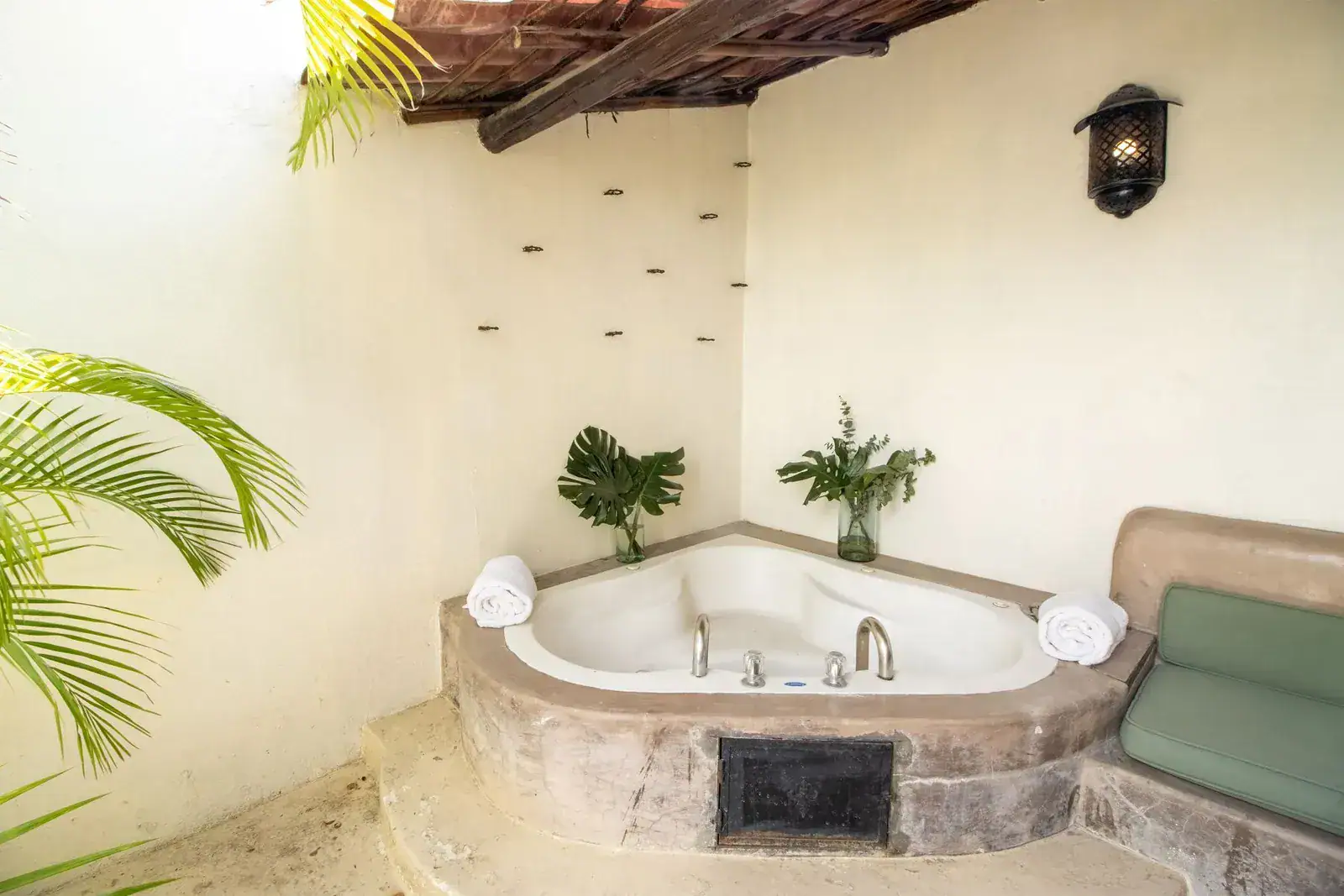 Casa Quetzal Hotel, corner bathtub on a stone platform with a green bench and palm fronds, San Miguel de Allende