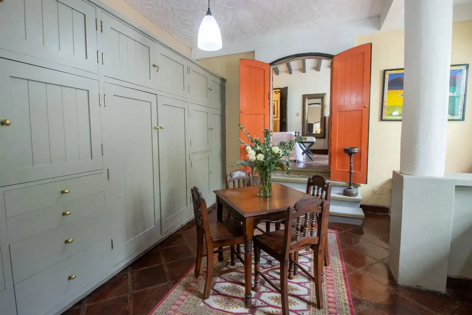Casa Quetzal Hotel, dining table and built-in gray cabinets with an orange door, San Miguel de Allende