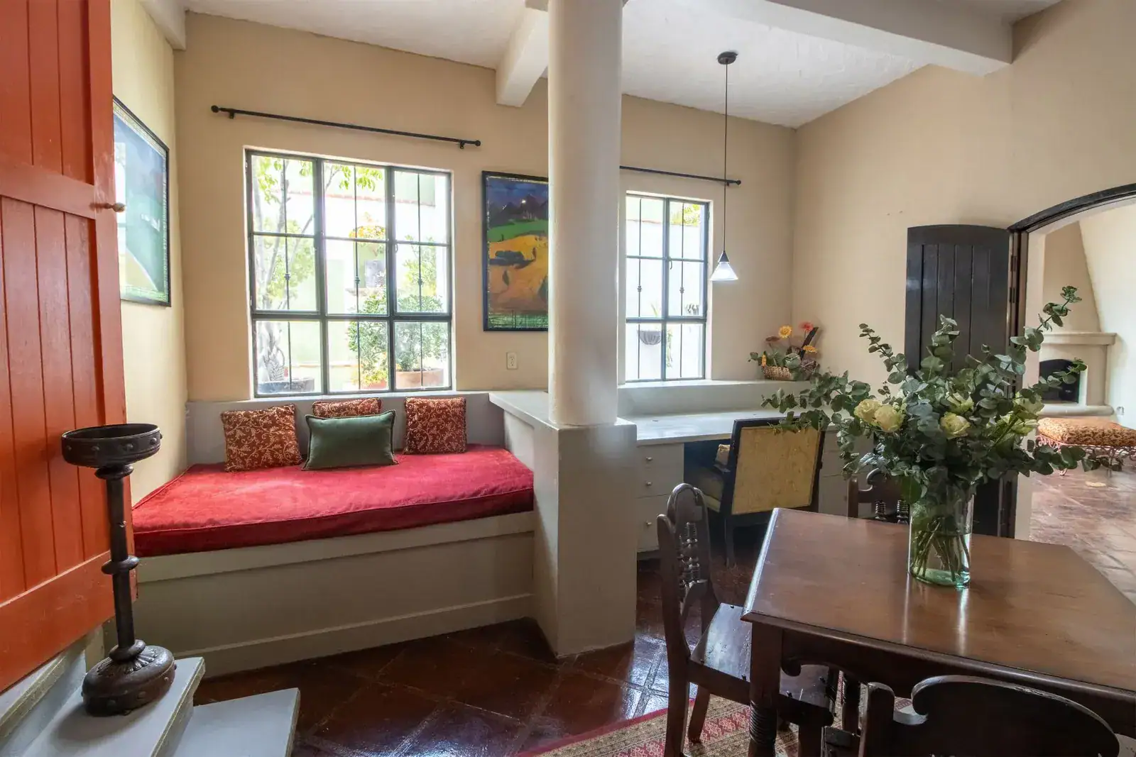 Casa Quetzal Hotel, window seat with red cushions beside a dining table and a stone column, San Miguel de Allende