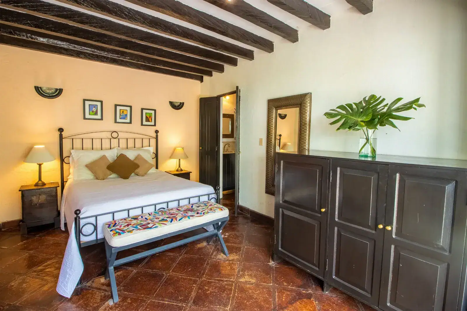 Casa Quetzal Hotel, bedroom with a wrought-iron bed, patterned bench and a beamed ceiling, San Miguel de Allende