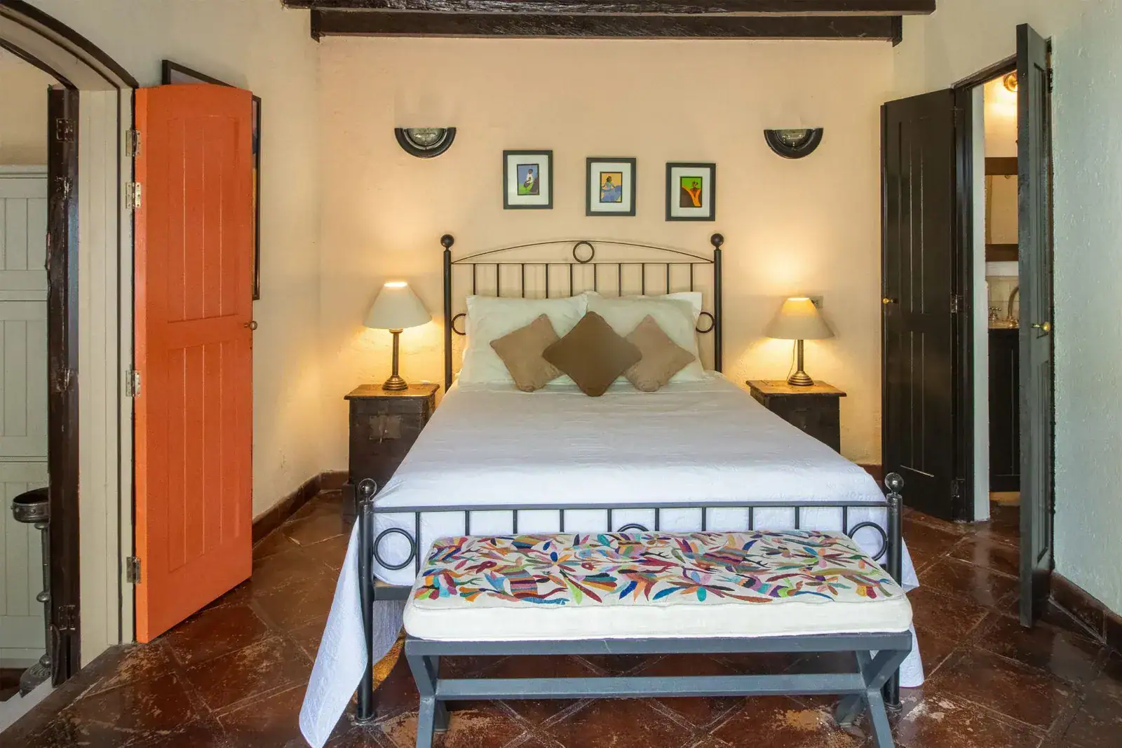 Casa Quetzal Hotel, bedroom with an iron bed, colorful embroidered bench and an orange shutter, San Miguel de Allende