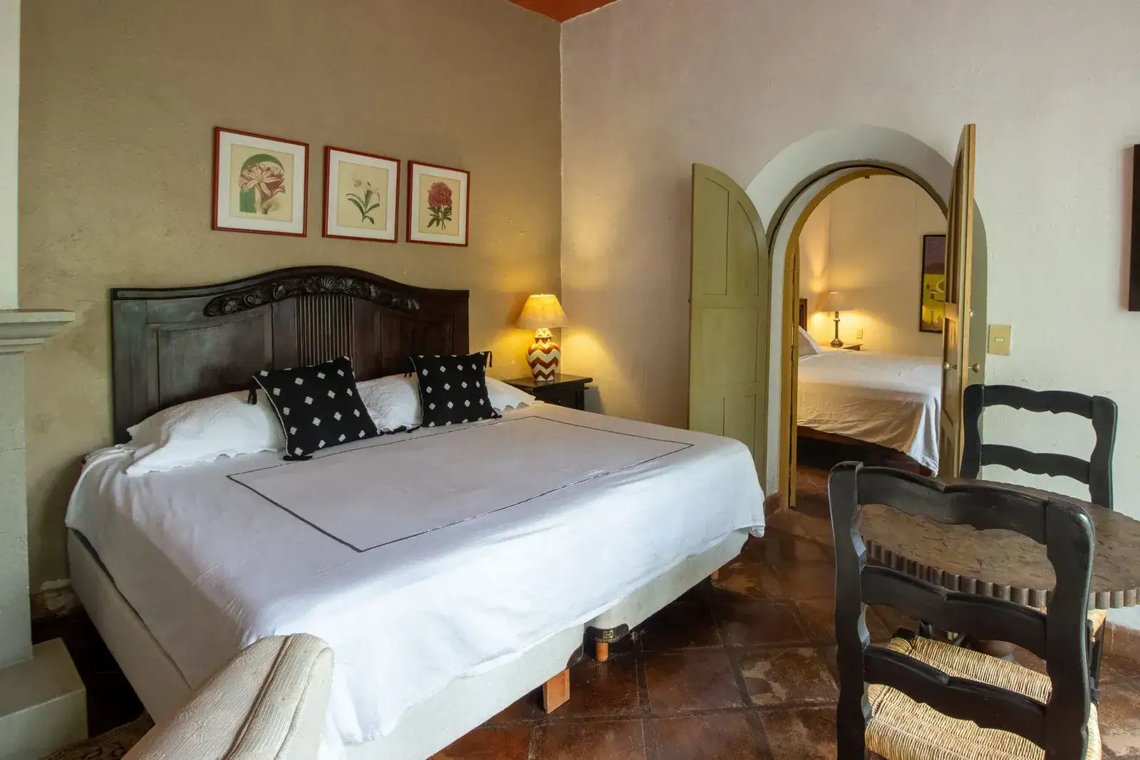 Casa Quetzal Hotel, bedroom with a carved wood headboard, black-and-white pillows and an arched doorway, San Miguel de Allende