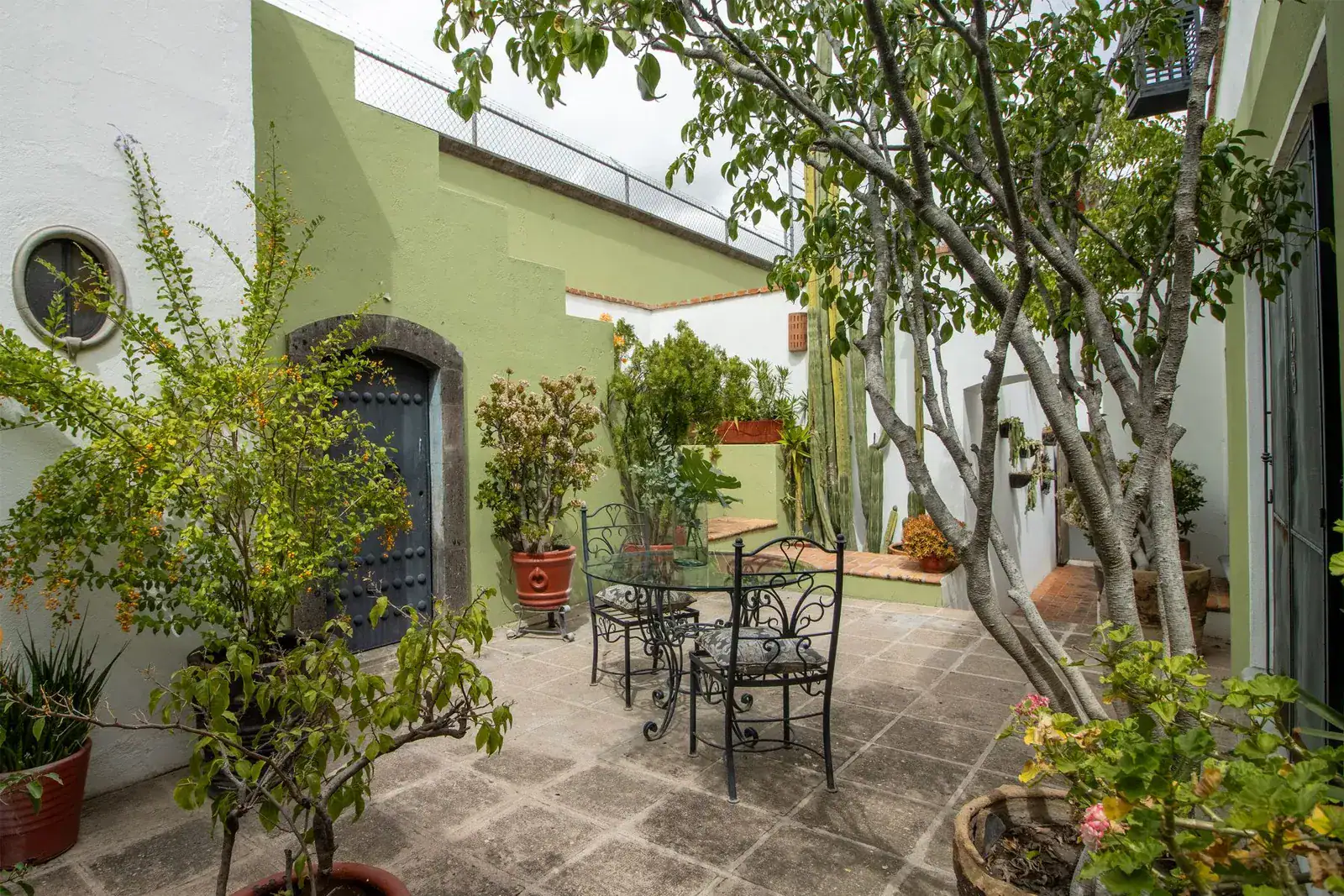Casa Quetzal Hotel, courtyard patio with a bistro table, potted plants and a green-and-white wall, San Miguel de Allende