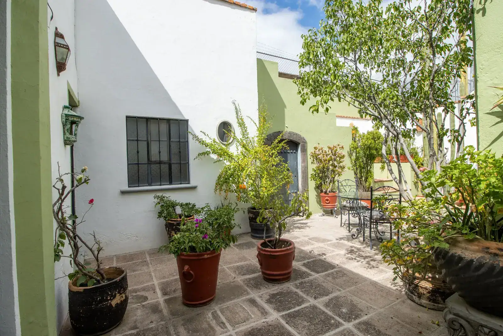 Casa Quetzal Hotel, courtyard with a small table, potted plants and a barred window, San Miguel de Allende