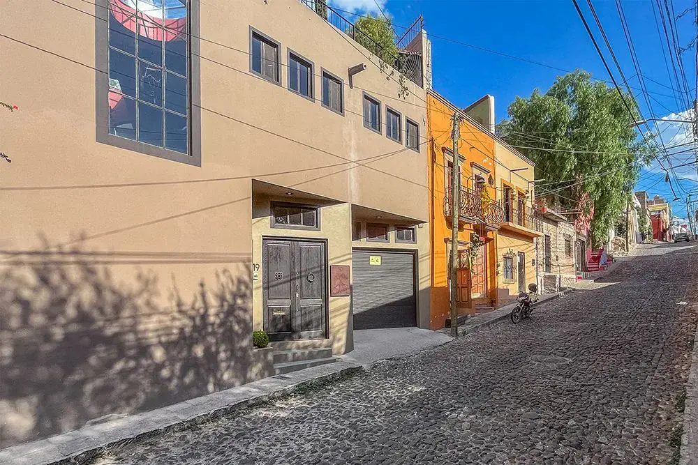 Casa Ro, street facade with a garage and a cobblestone street in Centro, San Miguel de Allende