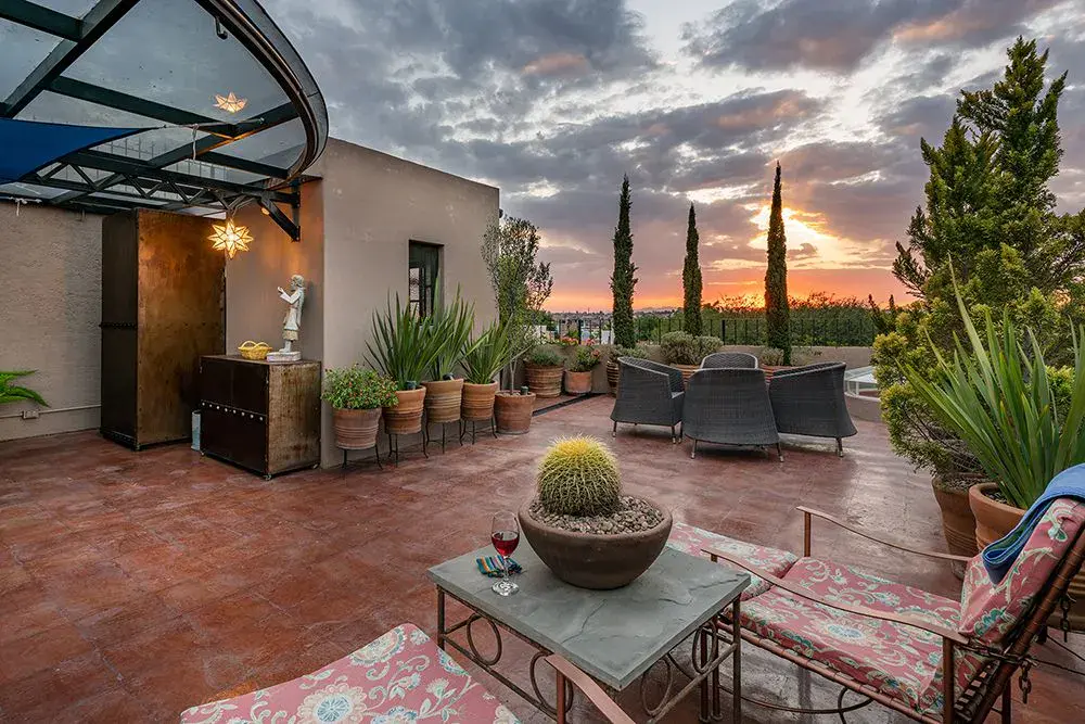 Casa Ro, rooftop terrace with potted plants and lounge chairs at sunset, San Miguel de Allende