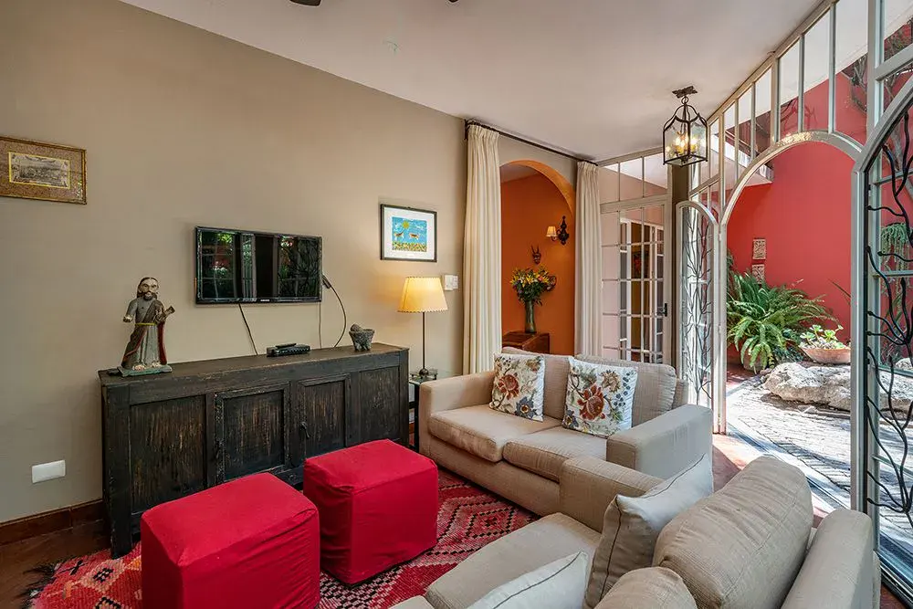 Casa Ro, living room with a sofa and red ottomans opening to the courtyard, San Miguel de Allende