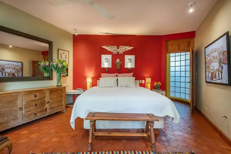 Casa Ro, primary bedroom with a red accent wall and a white bed, San Miguel de Allende