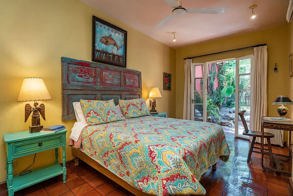 Casa Ro, bedroom with a carved headboard and colorful bedding, San Miguel de Allende