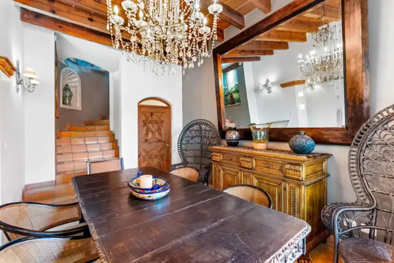 Casa Roka, dining table with a peacock chair, a carved sideboard, a large wood-framed mirror and a stair, San Miguel de Allende