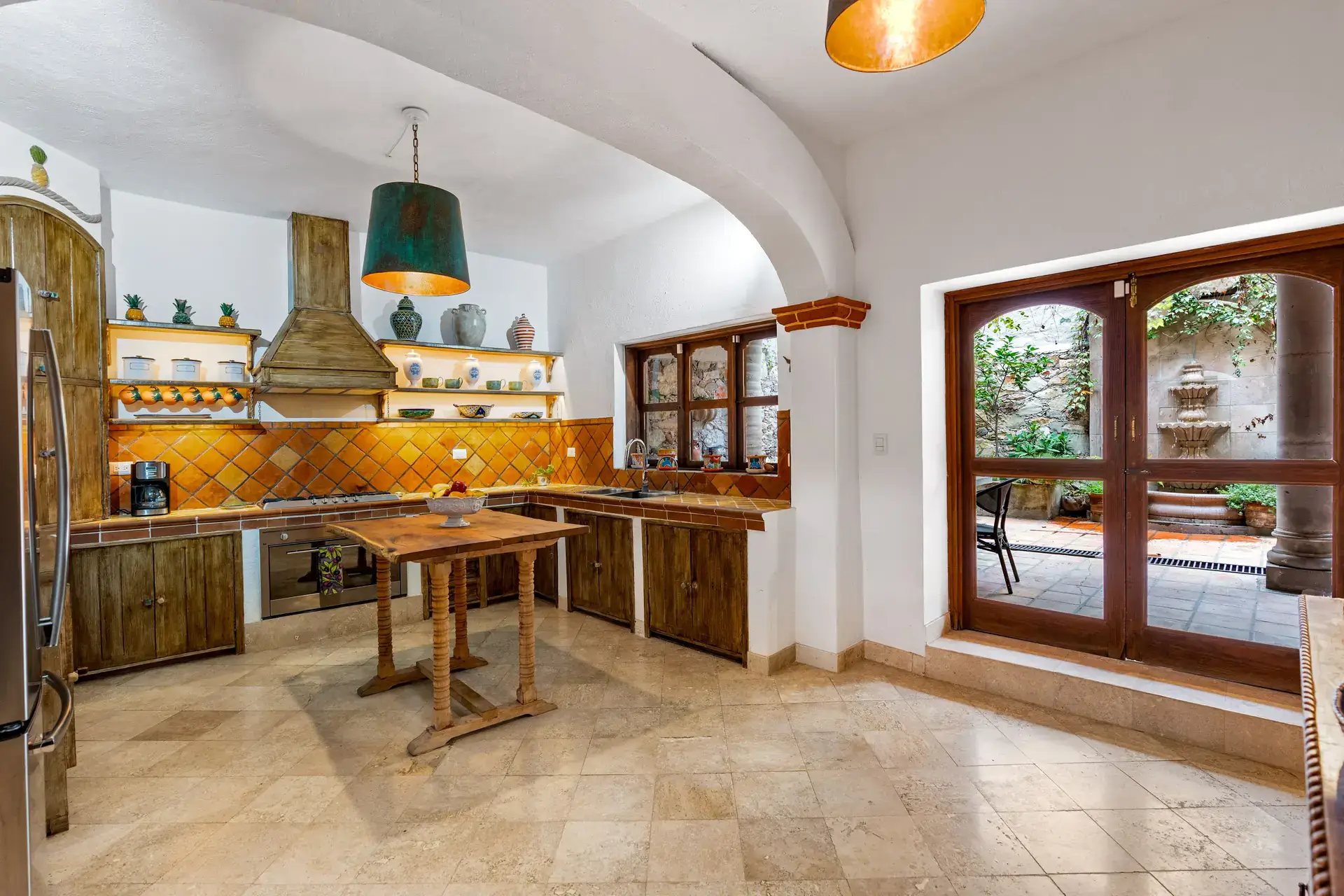 Casa Roka, kitchen with rustic wood cabinets, orange diagonal tile, a copper-toned hood and a wood island, San Miguel de Allende