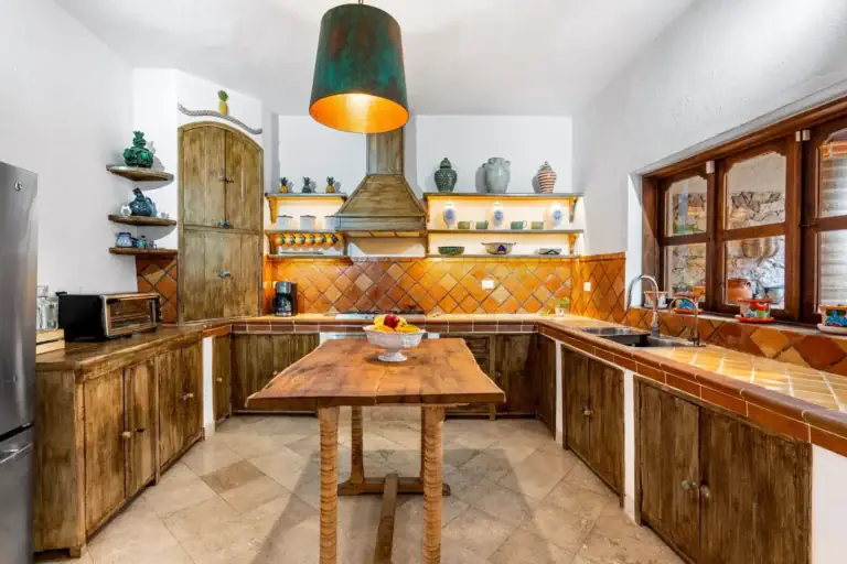 Casa Roka, kitchen with a green copper-lined pendant lamp, open shelves of ceramics and a wood island, San Miguel de Allende