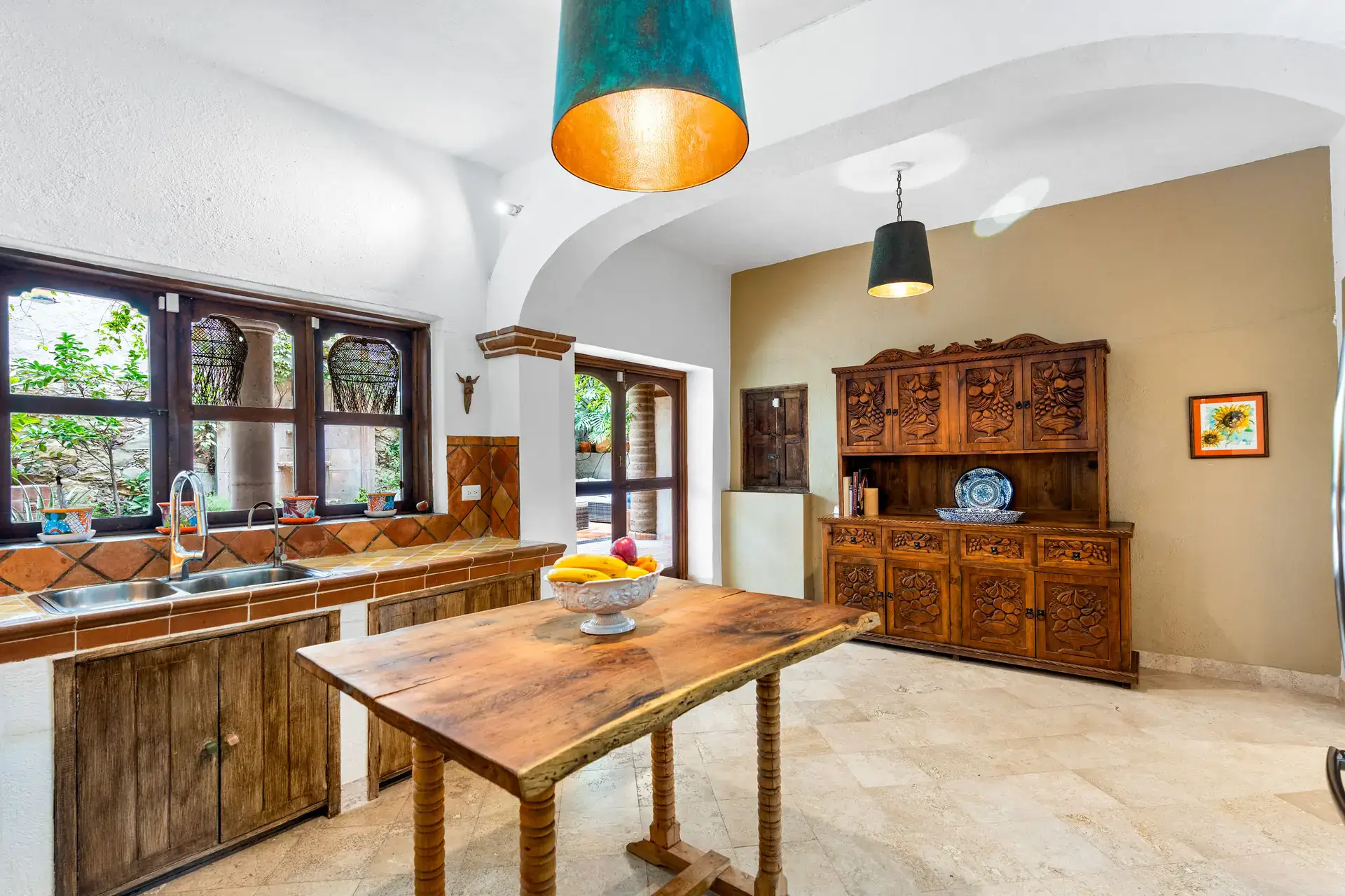 Casa Roka, kitchen with a wood island, double sinks, a carved wood hutch and wood windows, San Miguel de Allende