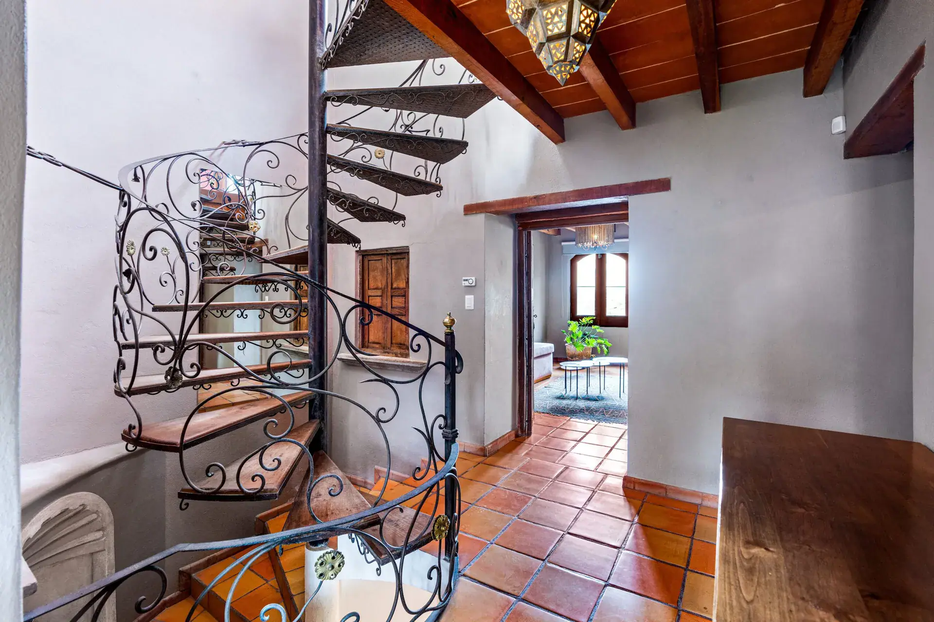 Casa Roka, ornate wrought-iron spiral staircase at the center of the house with terracotta tile floors, San Miguel de Allende
