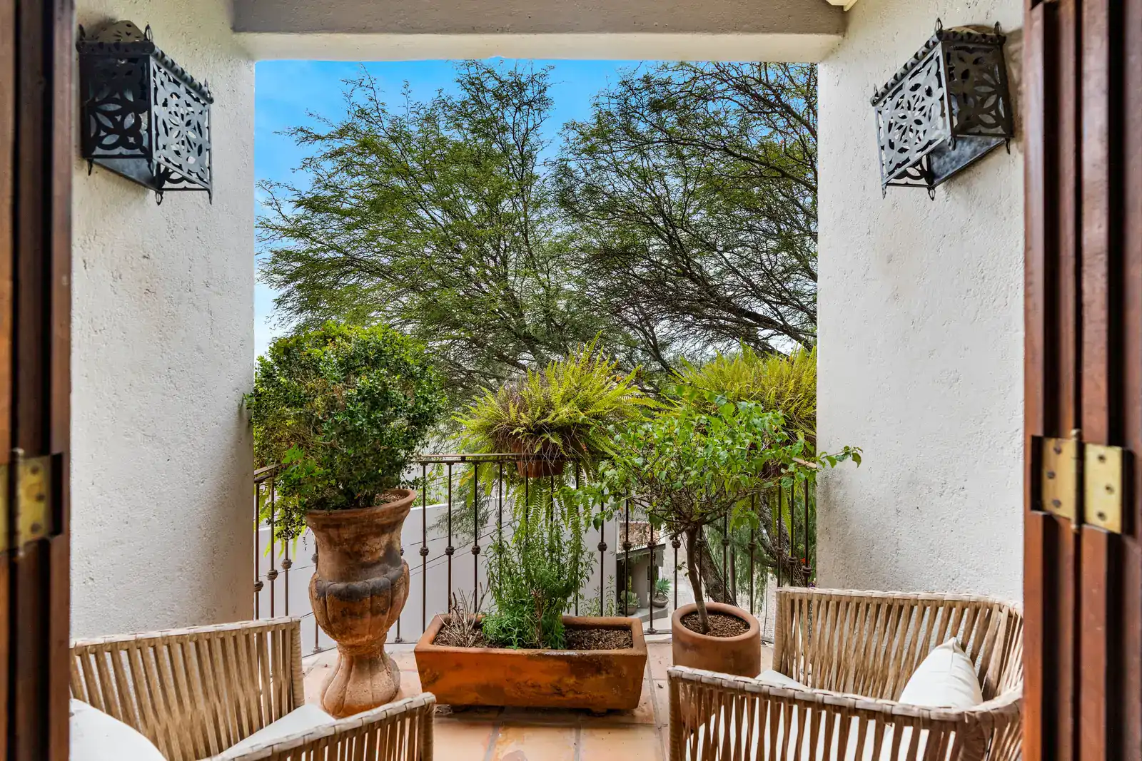 Casa Roka, balcony view through a wood door with potted plants and wicker chairs, San Miguel de Allende