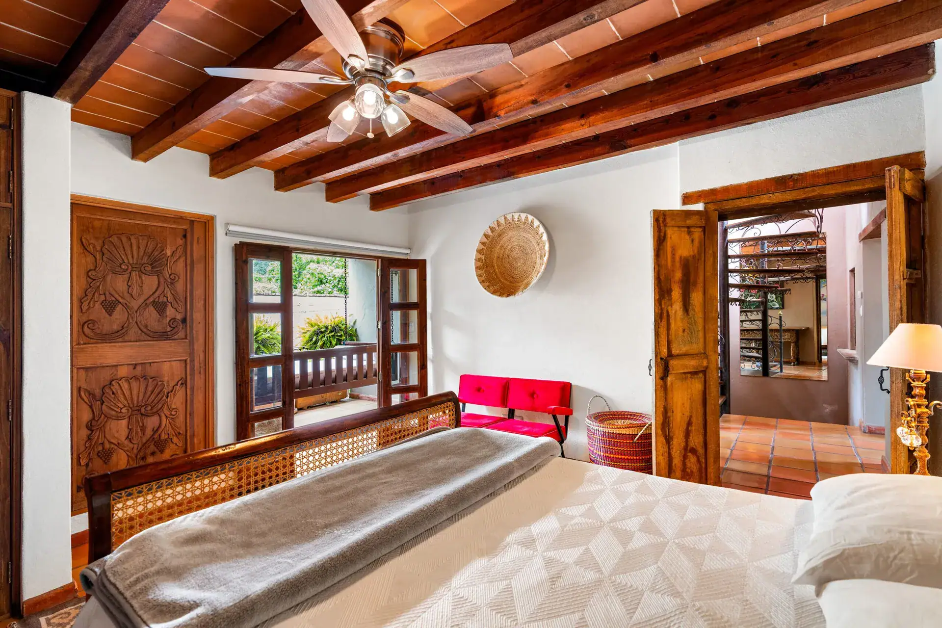 Casa Roka, bedroom with a carved wood armoire, a cane bed, a ceiling fan and doors to a balcony, San Miguel de Allende